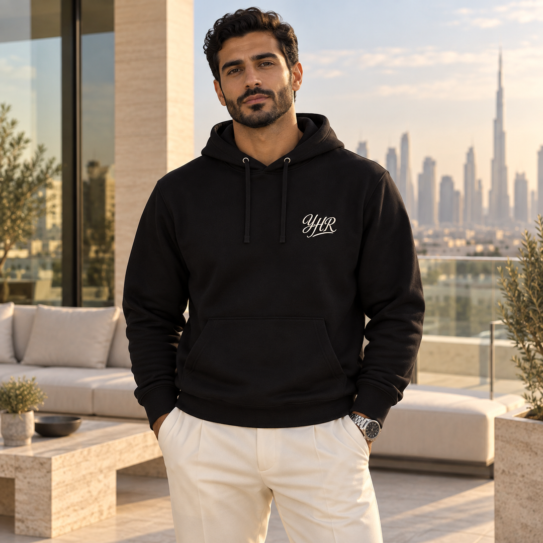 AI-generated lifestyle styling image of the black YHR Script Classic Pullover Hoodie on an upscale terrace.