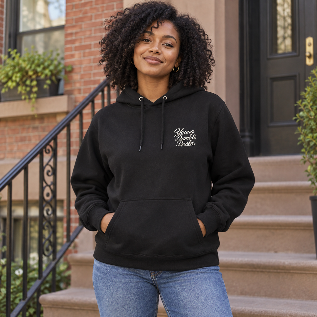 AI-generated lifestyle styling image of the black Young Dumb & Broke Classic Pullover Hoodie in a neighborhood setting.