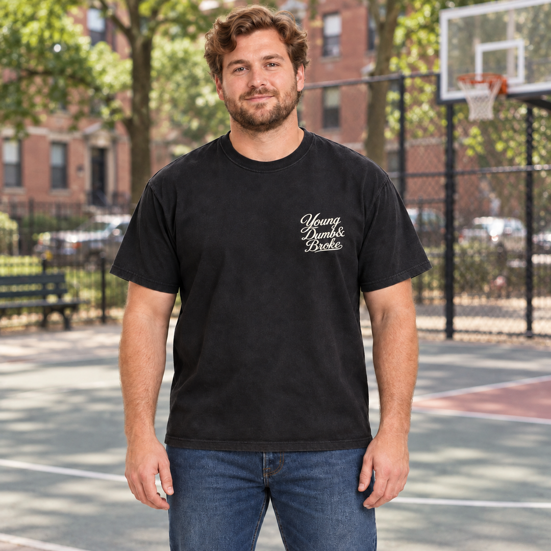 AI-generated lifestyle styling image of Young Dumb & Broke Garment-Dyed Heavyweight T-Shirt – Dark in an everyday neighborhood setting.